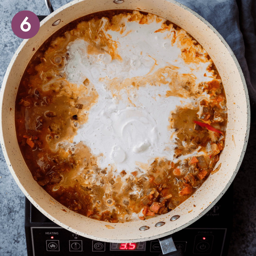 coconut milk poured into a saucepan with sauteed Thai aromatics.