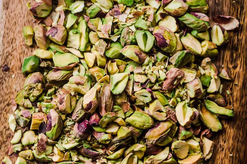 chopped pistachios on a wooden cutting board.