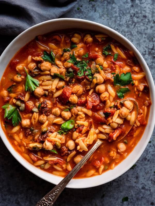 Instant Pot Chickpea Orzo Soup in white bowl with spoon.
