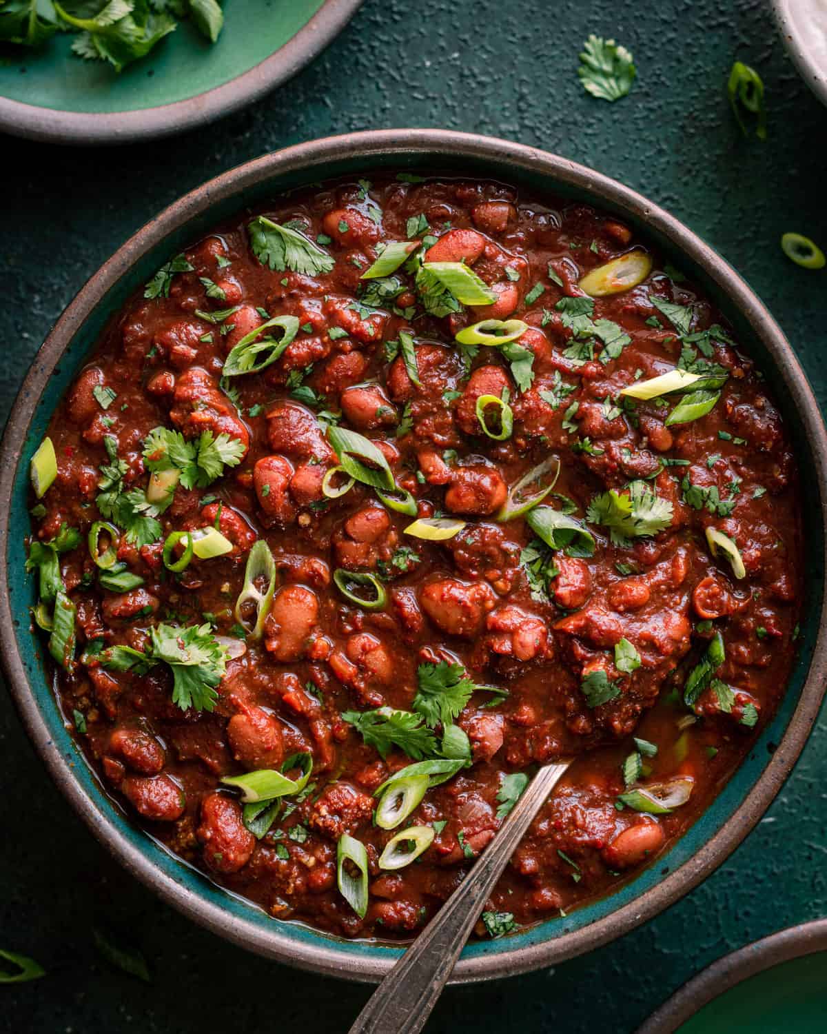 bowl of chili garnished with cilantro and scallions.