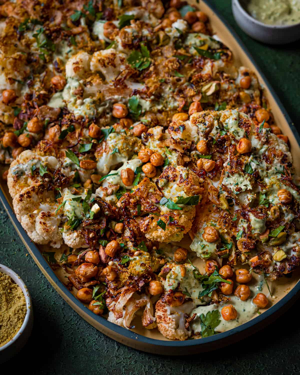 roasted cauliflower steaks and chickpeas with caramelized shallots and tahini sauce on yellow tray