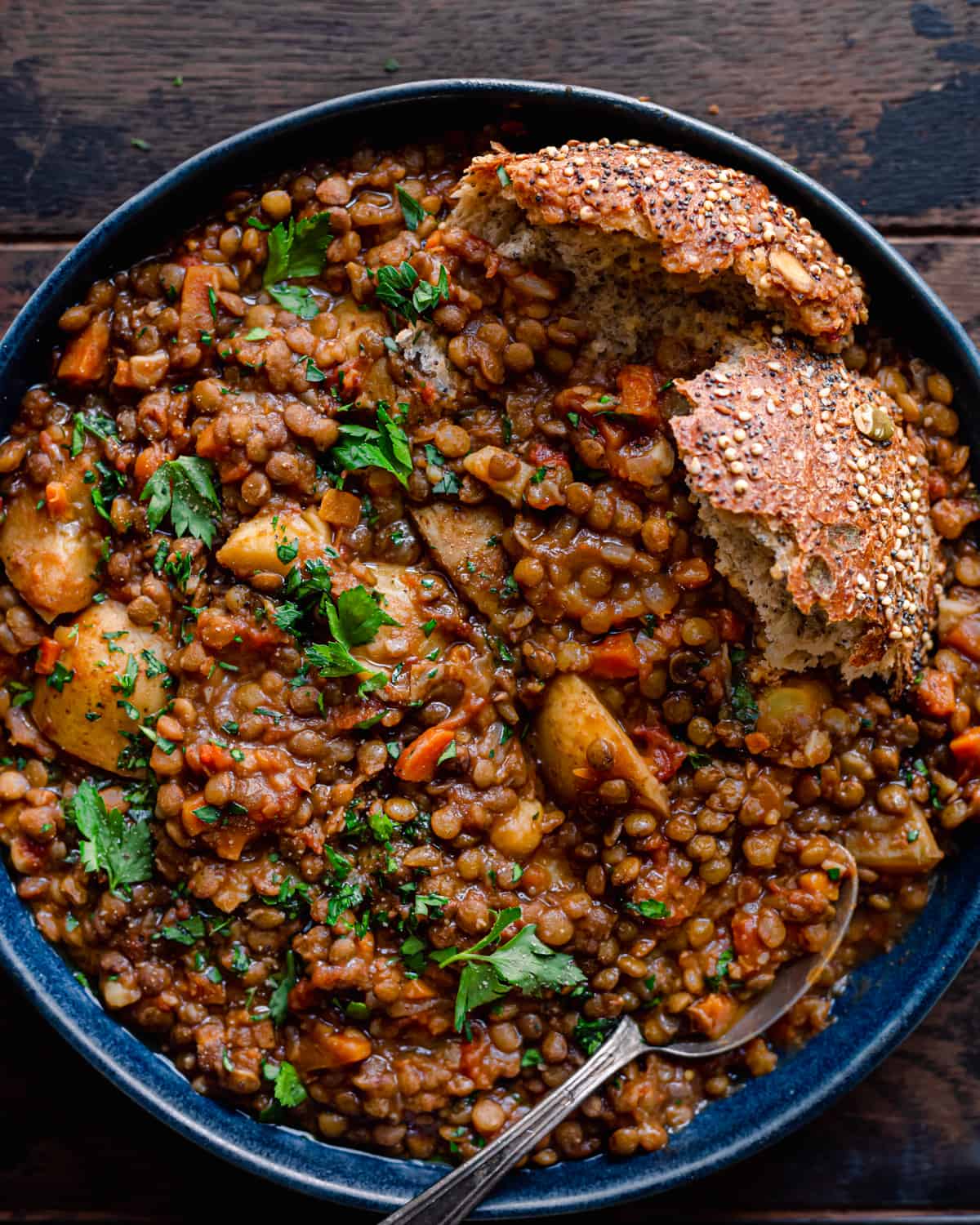 instant pot lentil soup in blue bowl with seeded bread on wooden table