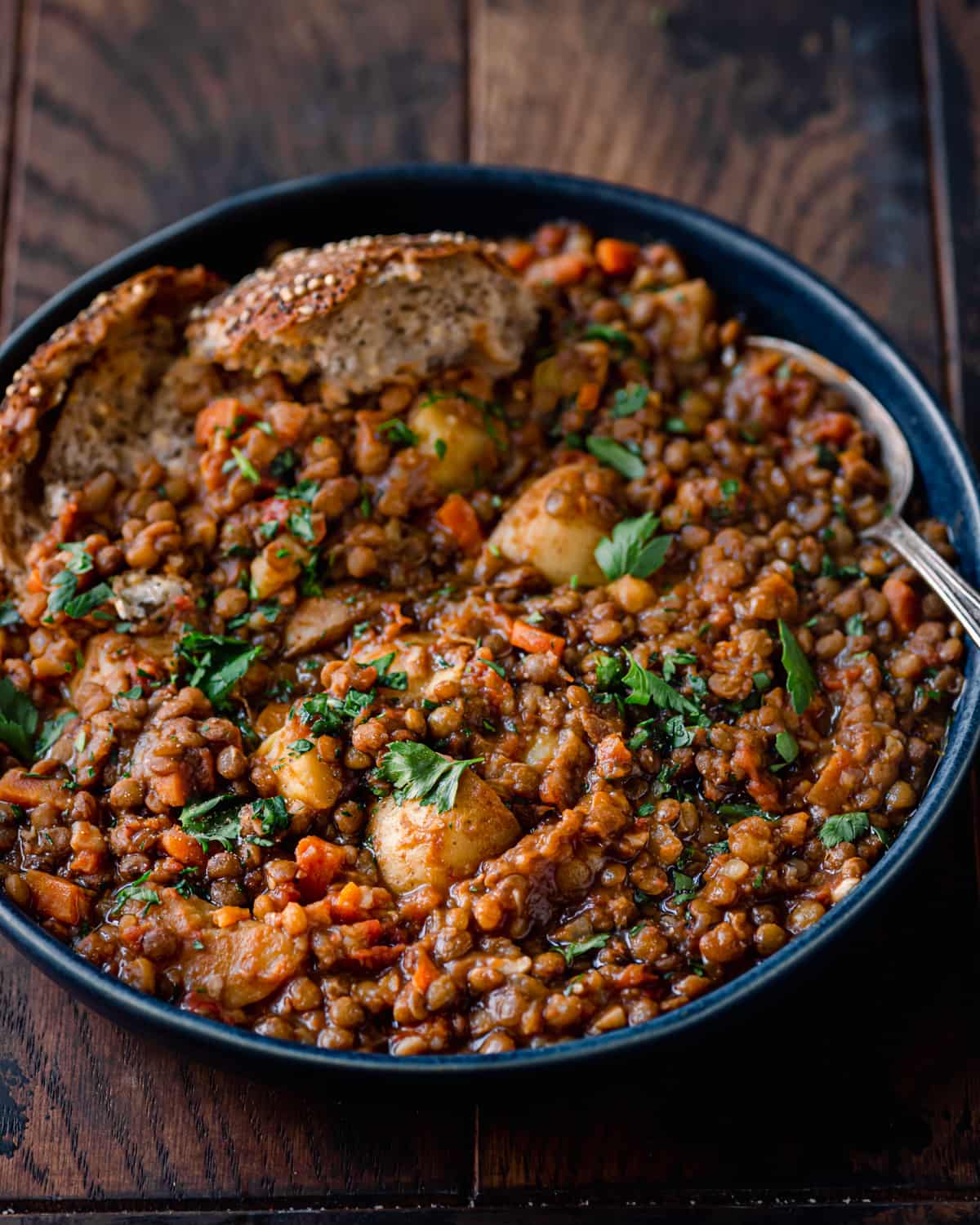 instant pot lentil soup in blue bowl with seeded bread on wooden table