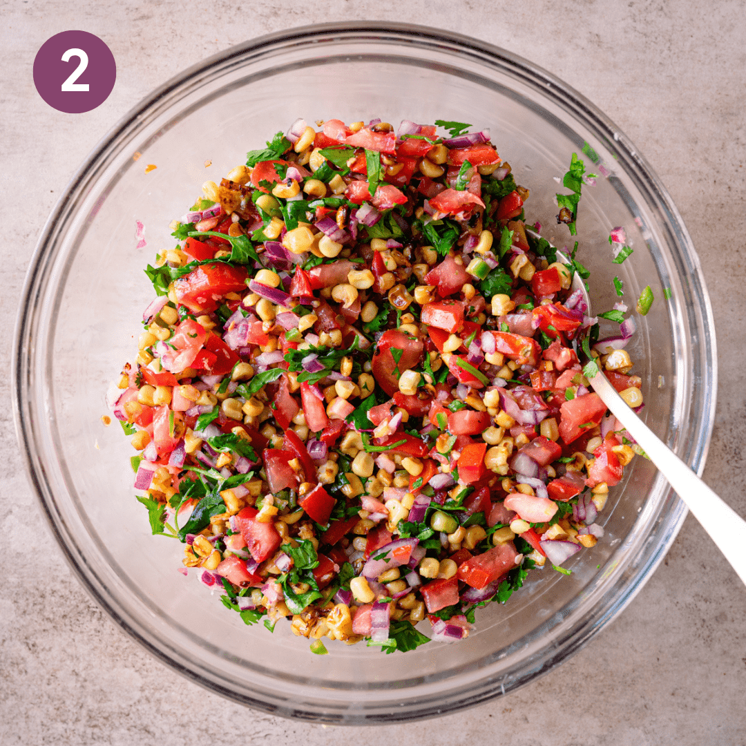 Corn salad ingredients in a glass bowl after being mixed.