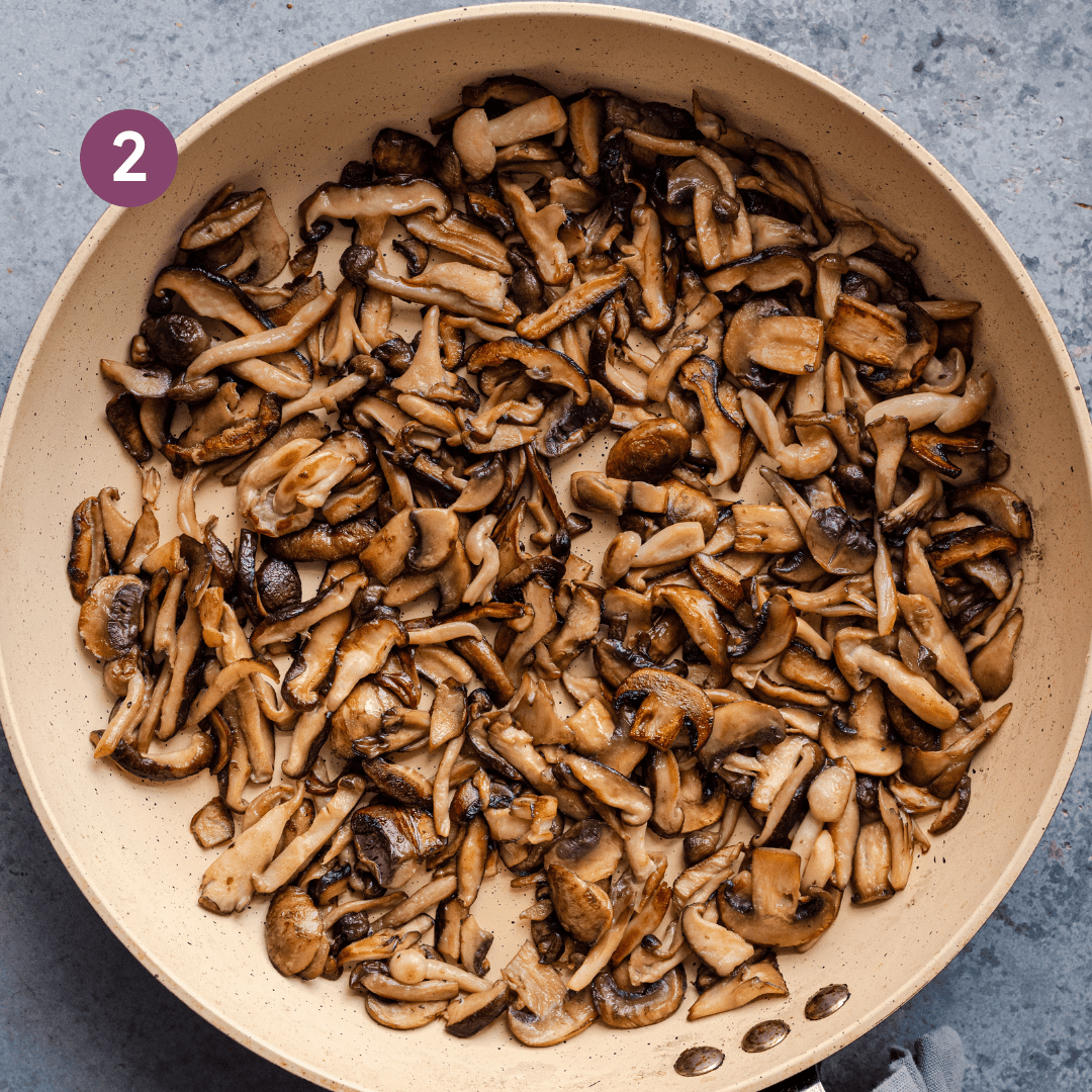 sliced mushrooms sauteing in a pan, looking golden brown.