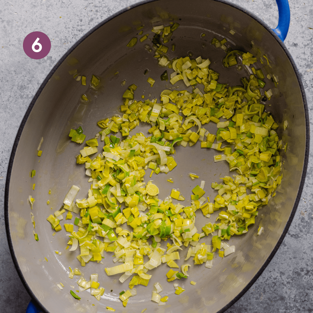 large dutch oven with leeks and garlic sauteeing.