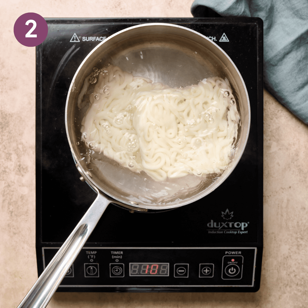 Udon noodles in saucepan with boiling water.