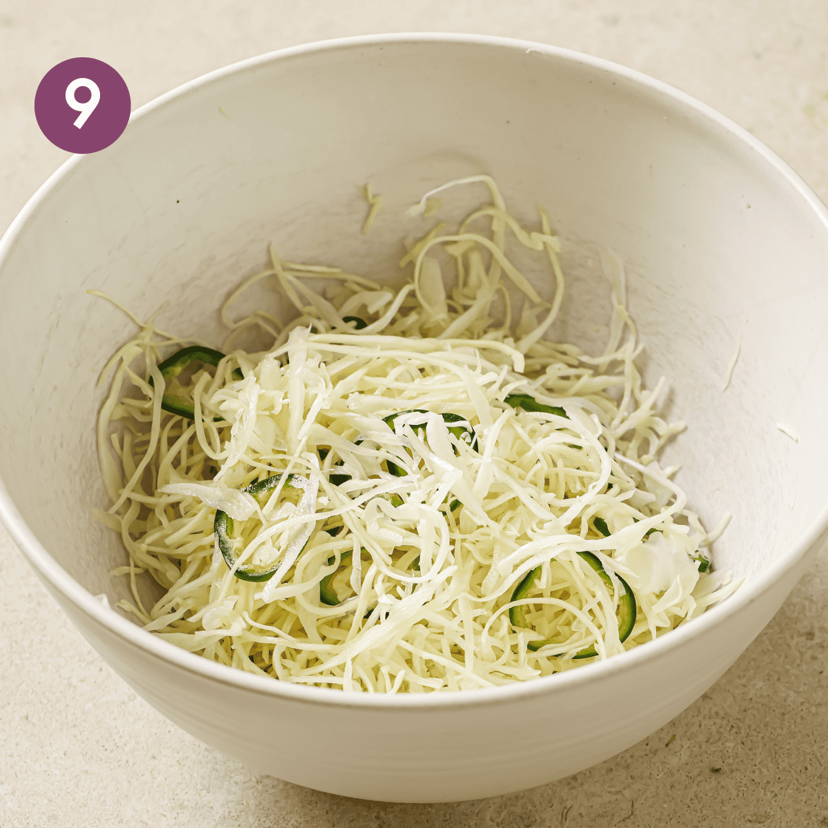cabbage slaw with sliced jalapenos in a cream bowl.