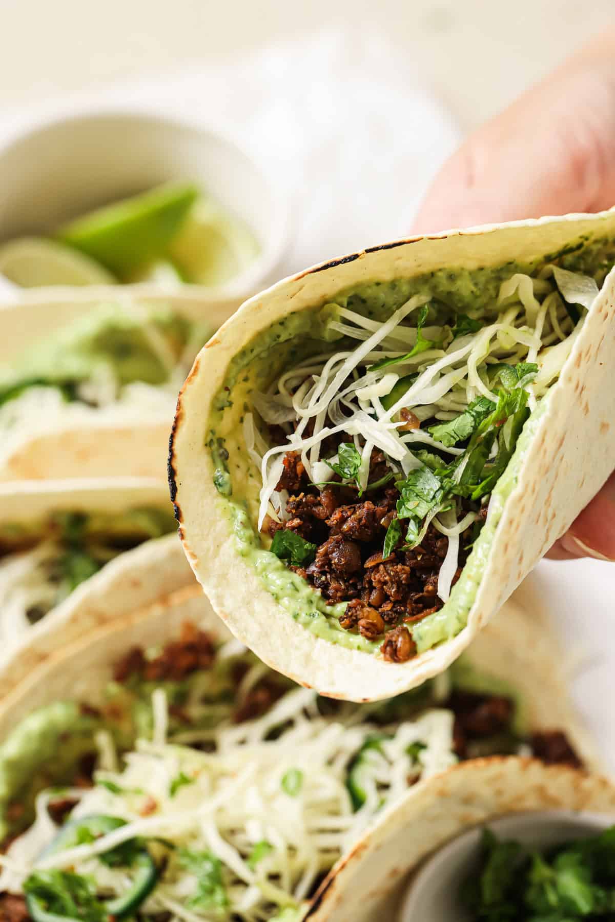 woman's hand holding up a lentil taco with slaw and avocado crema.
