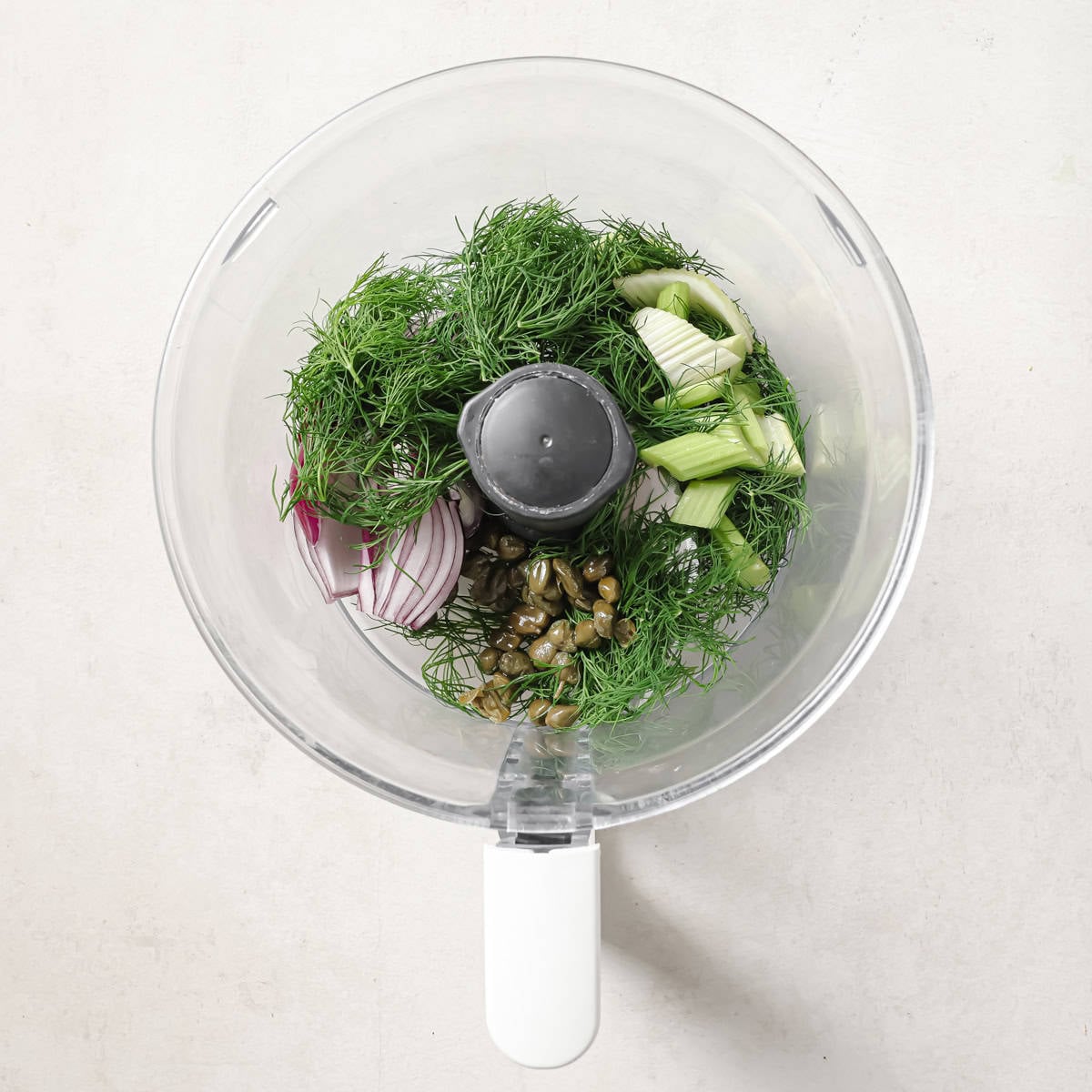 onion, celery, dill, and capers in a food processor before being pulsed.