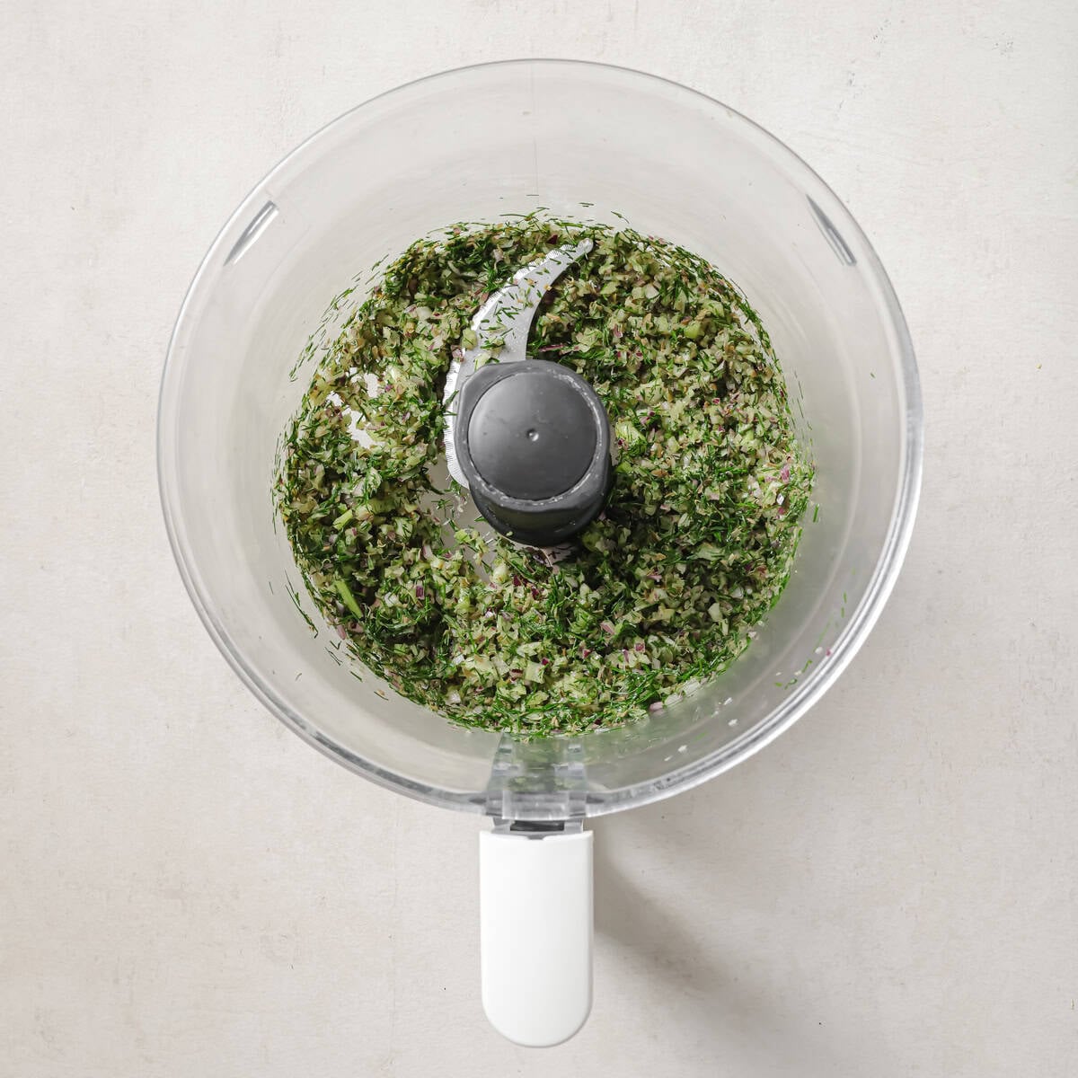onion, celery, dill, and capers in a food processor after being pulsed.