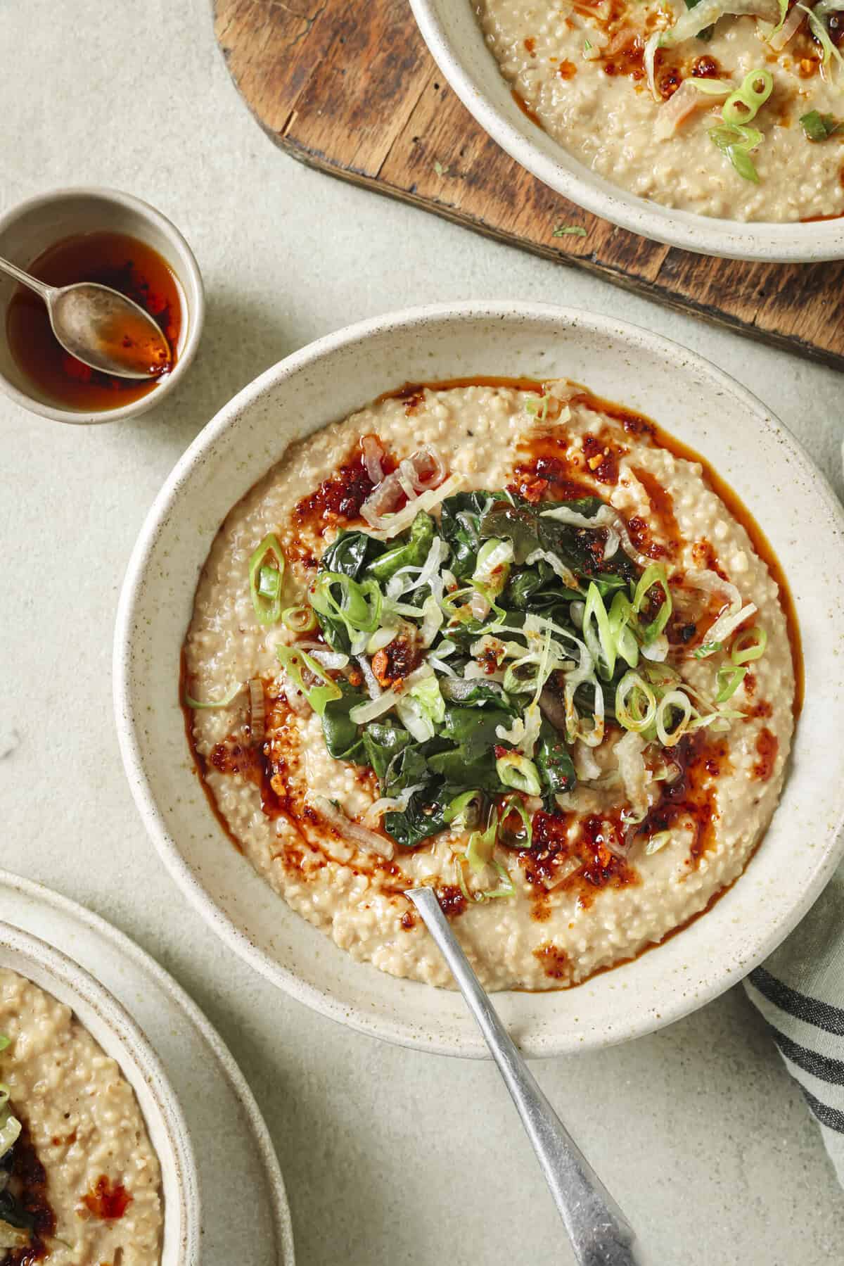 Close-up of bowl of savory oatmeal next to a small bowl of chili oil.