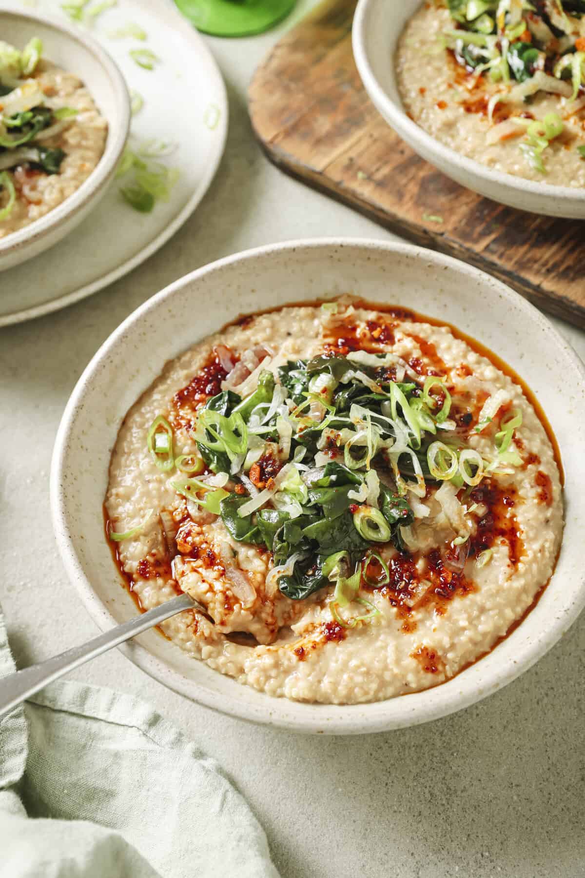 side view of three bowls of savory oatmeal on a table.