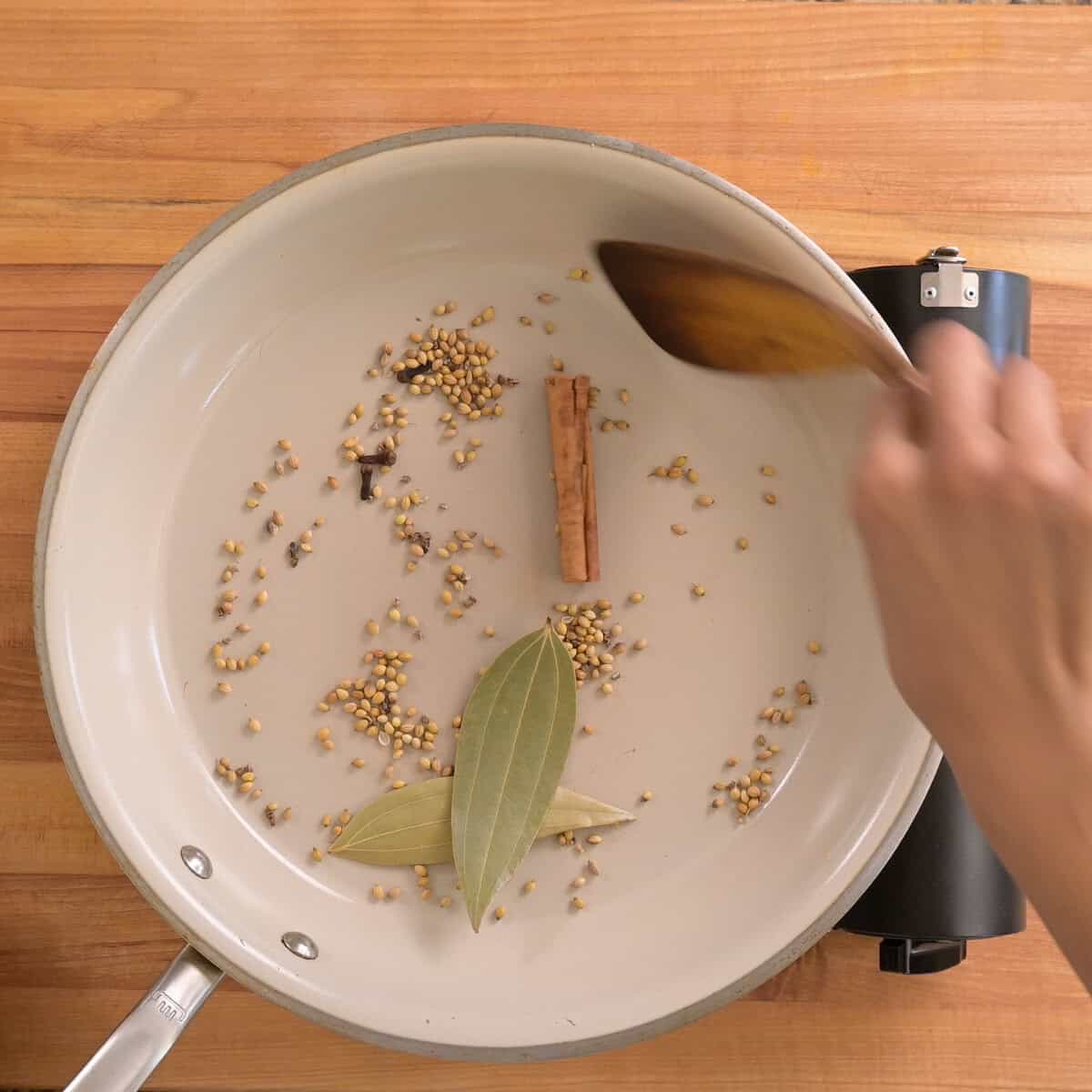 person stirring spices in pan.