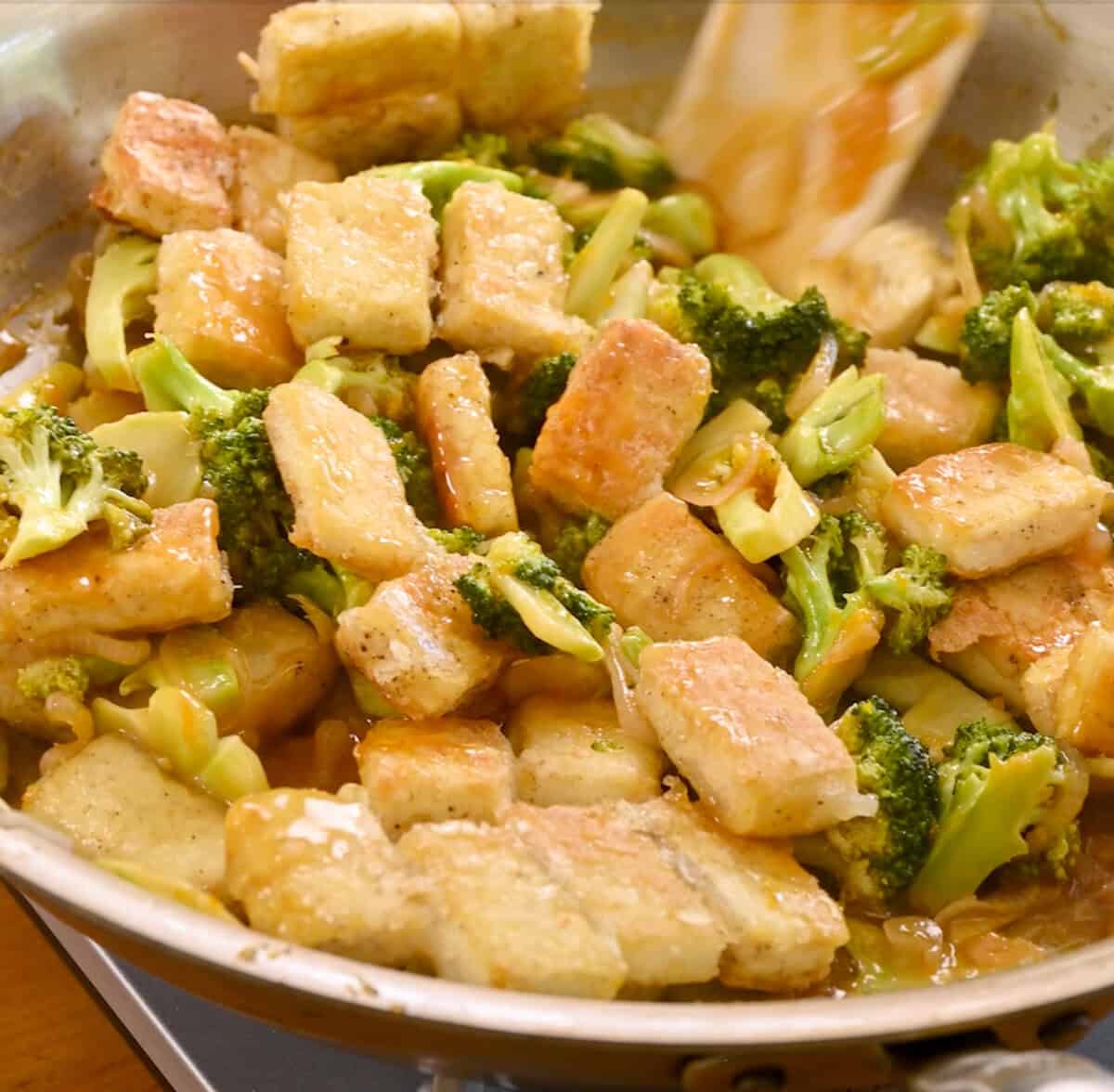 Orange sauce mixture combined with the tofu and broccoli in the frying pan.